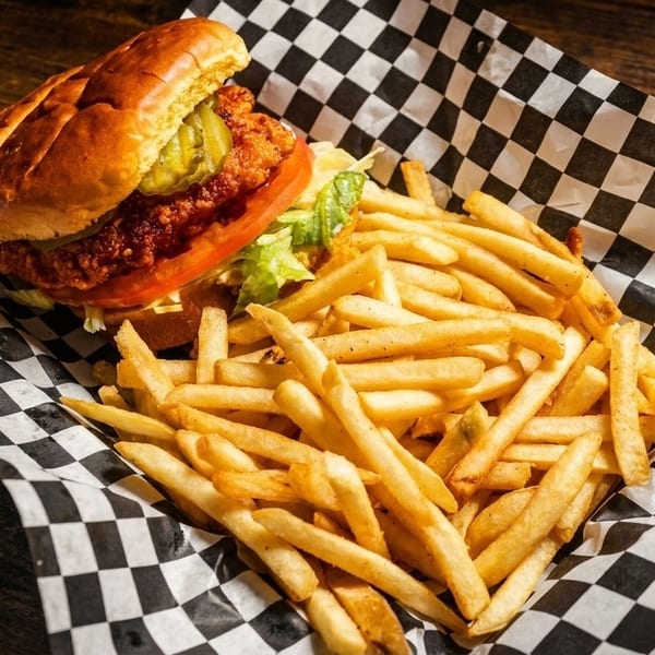 Crispy chicken sandwich with pickles, tomato, and lettuce, served with a side of golden fries.
